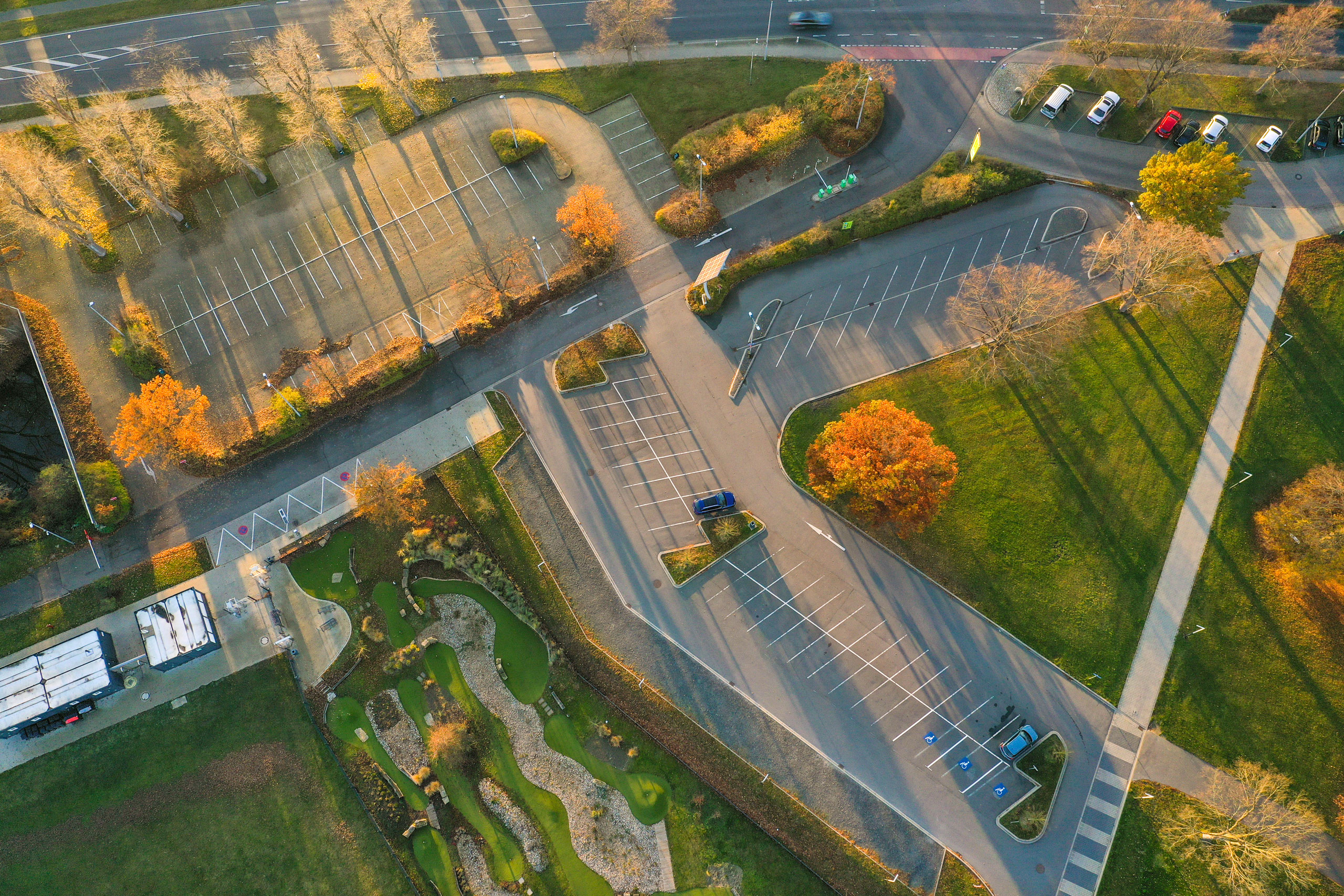Der leere Parkplatz des Stadtbads Okeraue aus der Vogelperspektive, im Abendsonnenlicht.