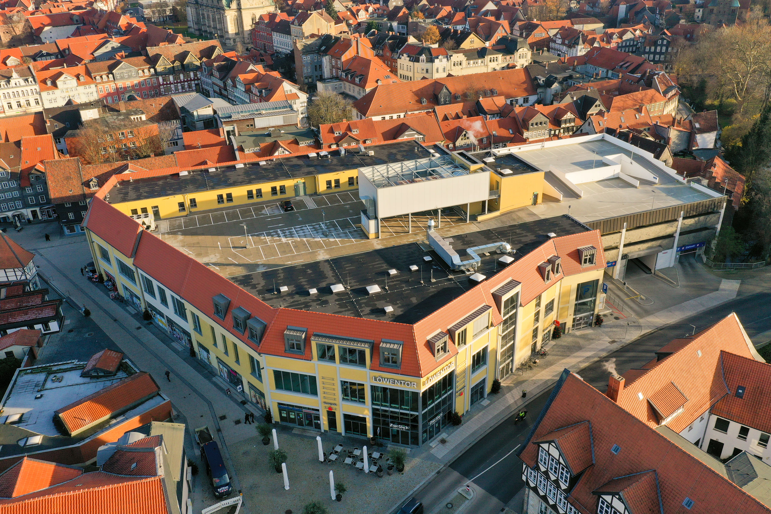 Ein Blick aus der Vogelperspektive auf das sonnige Parkhausdach eines zentral gelegenen Geschäftshausblocks mit der Aufschrift "Löwentor".